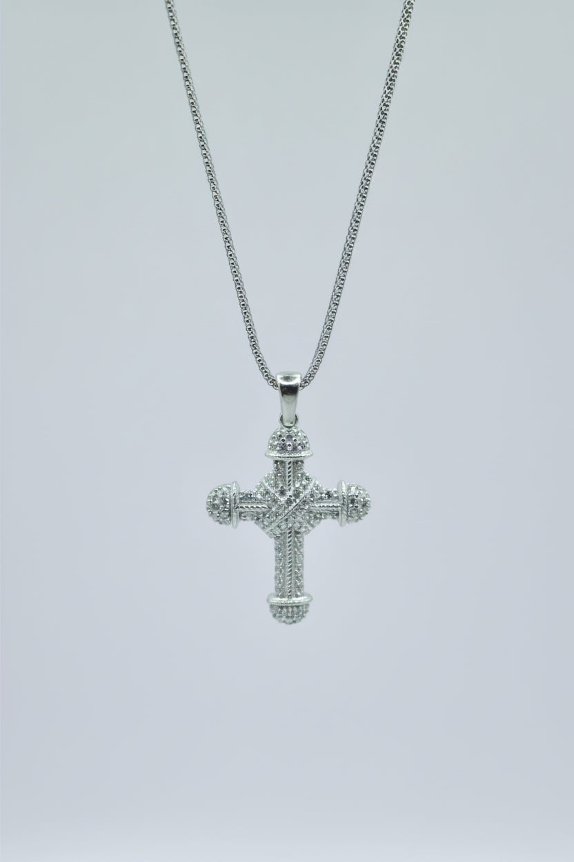 Silver cross pendant on a chain against a light gray background